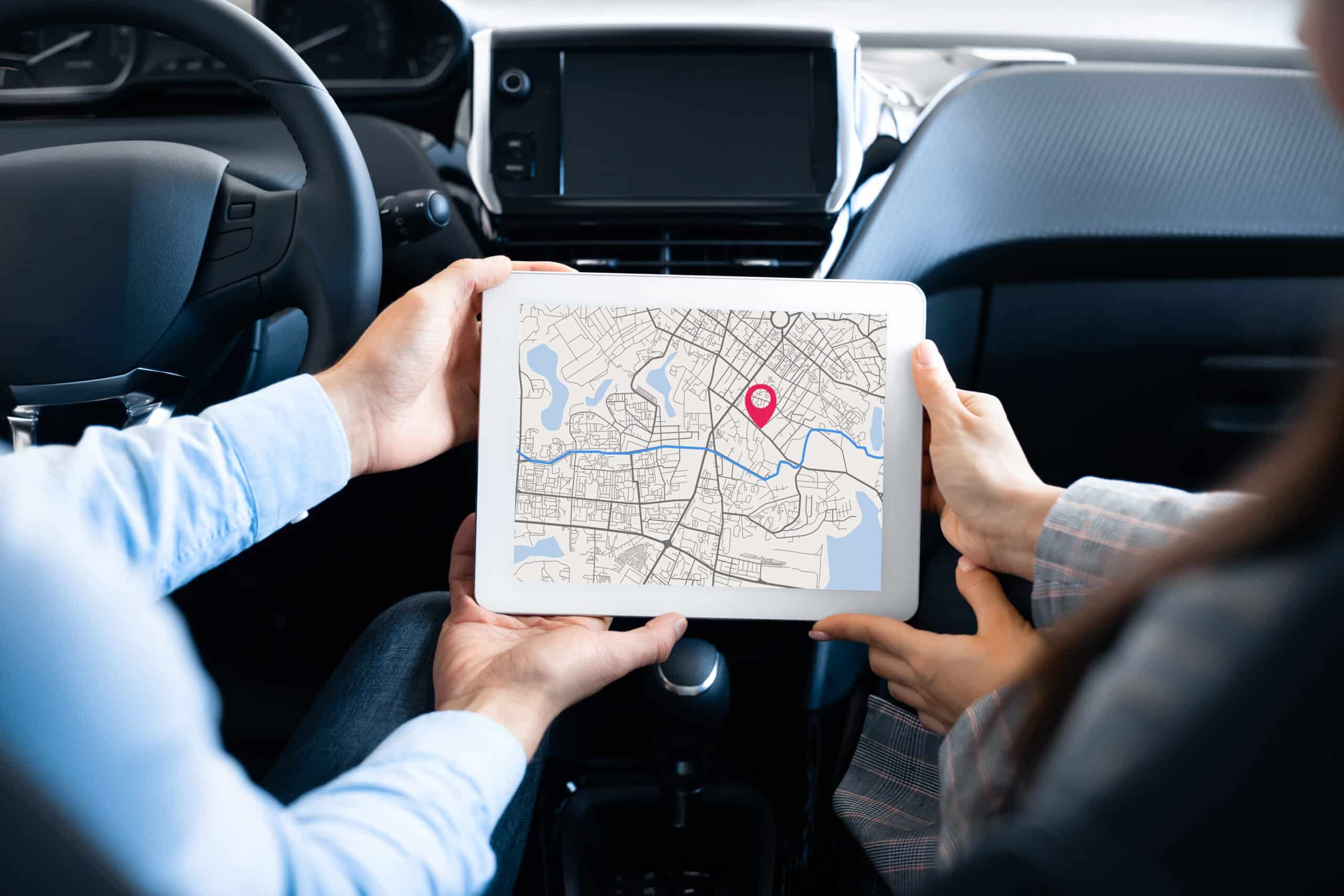 Closeup Of Couple Sitting In Car Using GPS Service On Digital Tablet