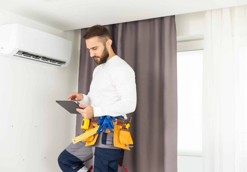 male technician service worker diagnosing for repairs air conditioner. person using tablet.